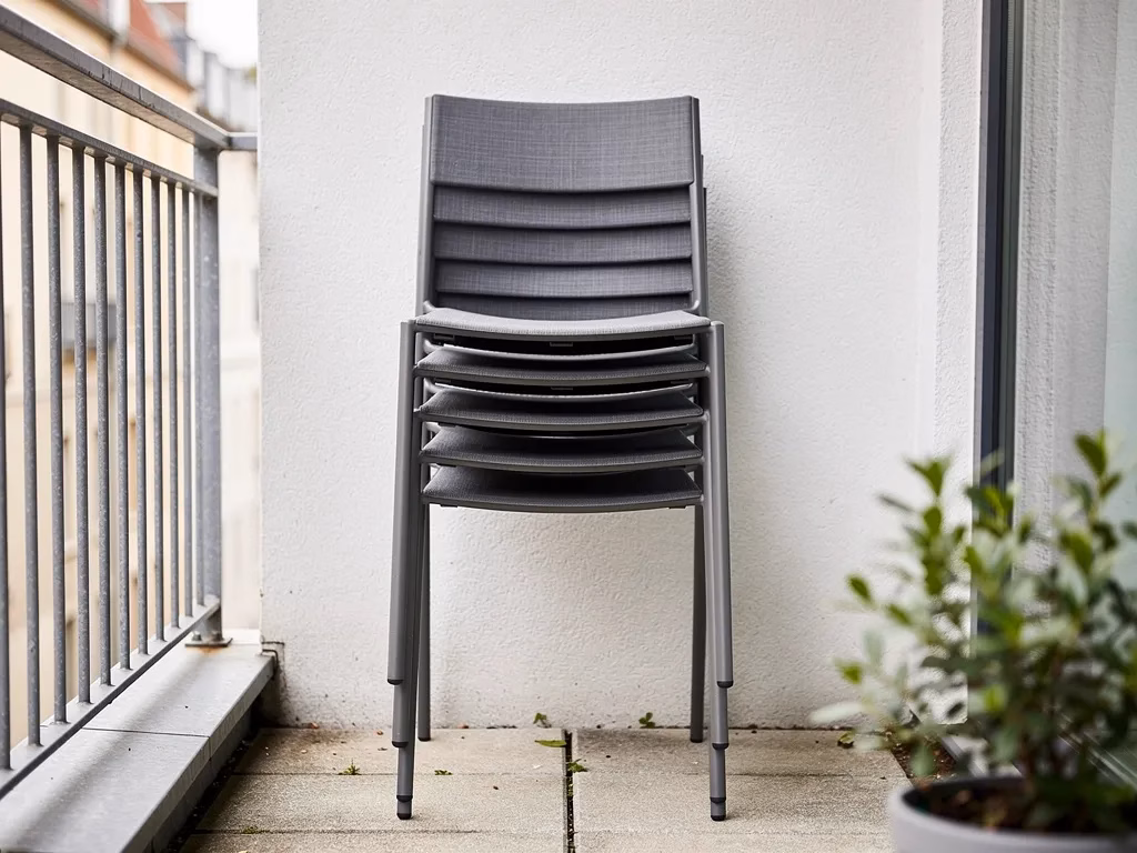 Stackable outdoor chairs vertically stacked on a small patio, space-saving furniture storage solution